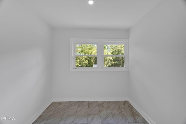 unfurnished room featuring baseboards, recessed lighting, and marble look tile flooring