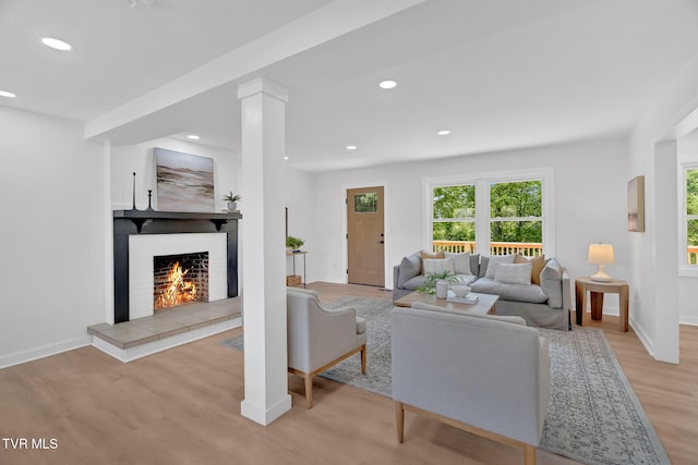 living area featuring light wood-type flooring, healthy amount of natural light, a fireplace, recessed lighting, and baseboards