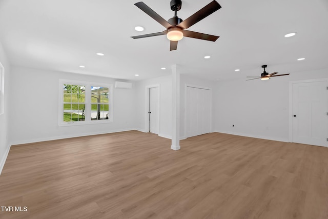 unfurnished living room featuring ceiling fan, recessed lighting, a wall mounted air conditioner, light wood-style flooring, and baseboards