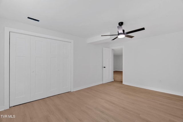 unfurnished bedroom featuring light wood-style floors, baseboards, and a closet