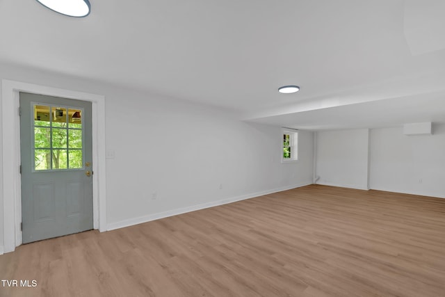 below grade area featuring light wood finished floors, plenty of natural light, and baseboards
