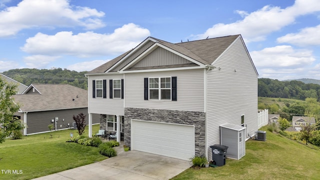 traditional-style house featuring an attached garage, driveway, a front yard, and stone siding