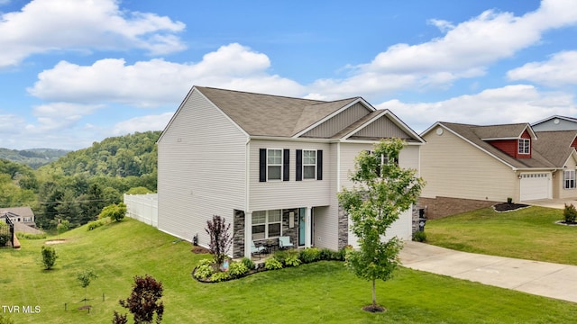 view of front facade with concrete driveway, a front yard, stone siding, covered porch, and roof with shingles