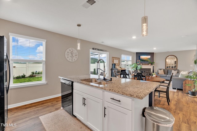 kitchen featuring a sink, black appliances, light wood-type flooring, baseboards, and pendant lighting