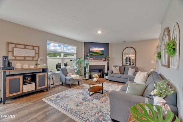 living area featuring wood finished floors, a glass covered fireplace, and recessed lighting