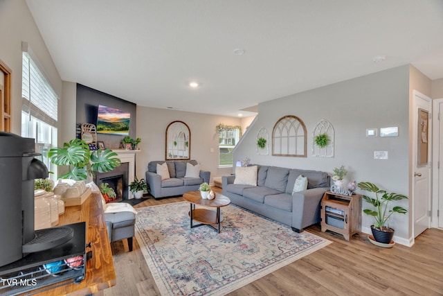 living room with light wood-type flooring, baseboards, a fireplace with flush hearth, and recessed lighting