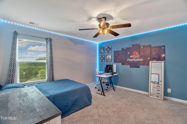 carpeted bedroom with an office area, a ceiling fan, and baseboards