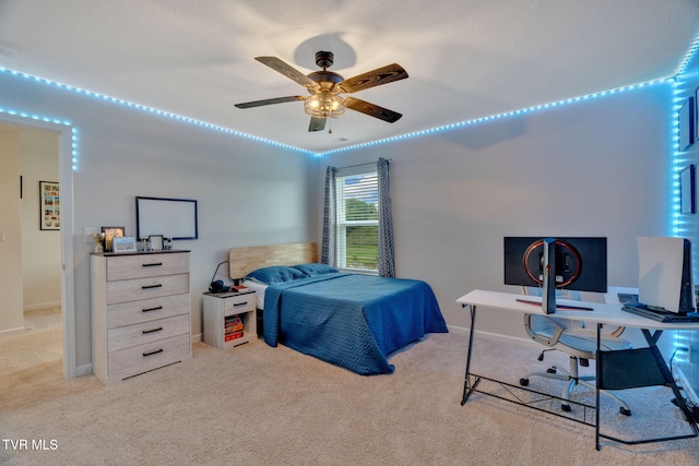 carpeted bedroom with a desk, baseboards, and ceiling fan