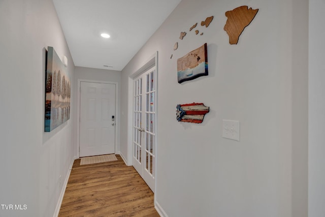 corridor featuring baseboards, wood finished floors, recessed lighting, and french doors