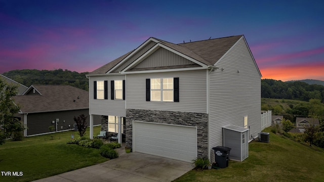 view of front facade with concrete driveway, a front yard, a garage, and stone siding