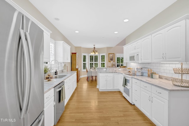 5 Fox Run Ln, Johnson City, TN 37604 - kitchen featuring stainless steel appliances, a peninsula, a sink, a chandelier, and light wood-style flooring