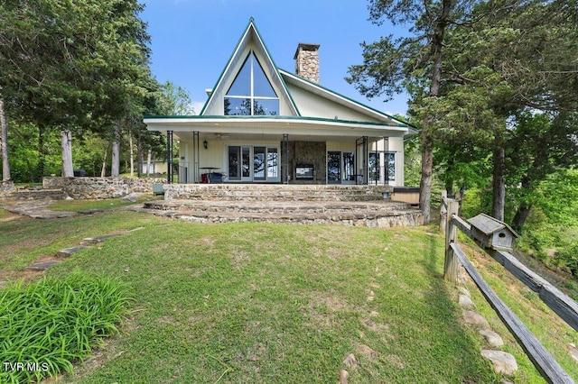 back of property featuring a chimney, a lawn, and french doors