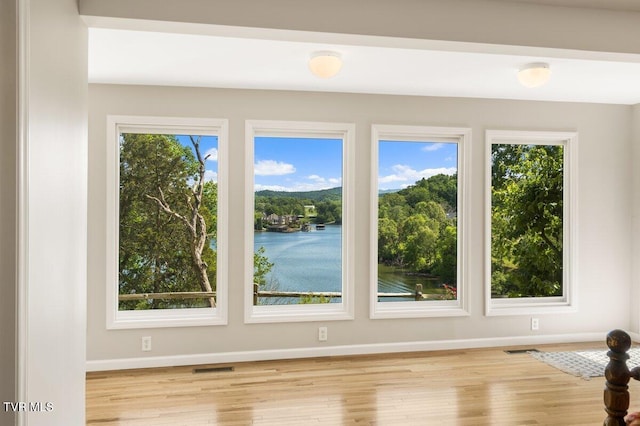 spare room with baseboards and wood finished floors