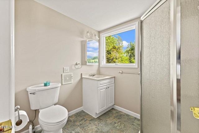 bathroom with baseboards, toilet, vanity, and stone finish flooring