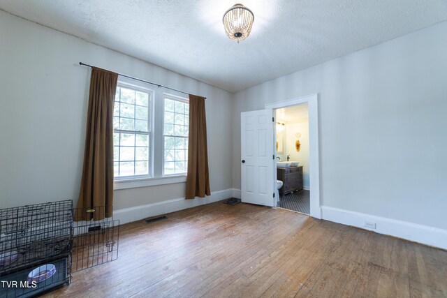 1496 Old State Route 34, Telford, TN 37690 - unfurnished bedroom featuring hardwood / wood-style floors, baseboards, a textured ceiling, and ensuite bath