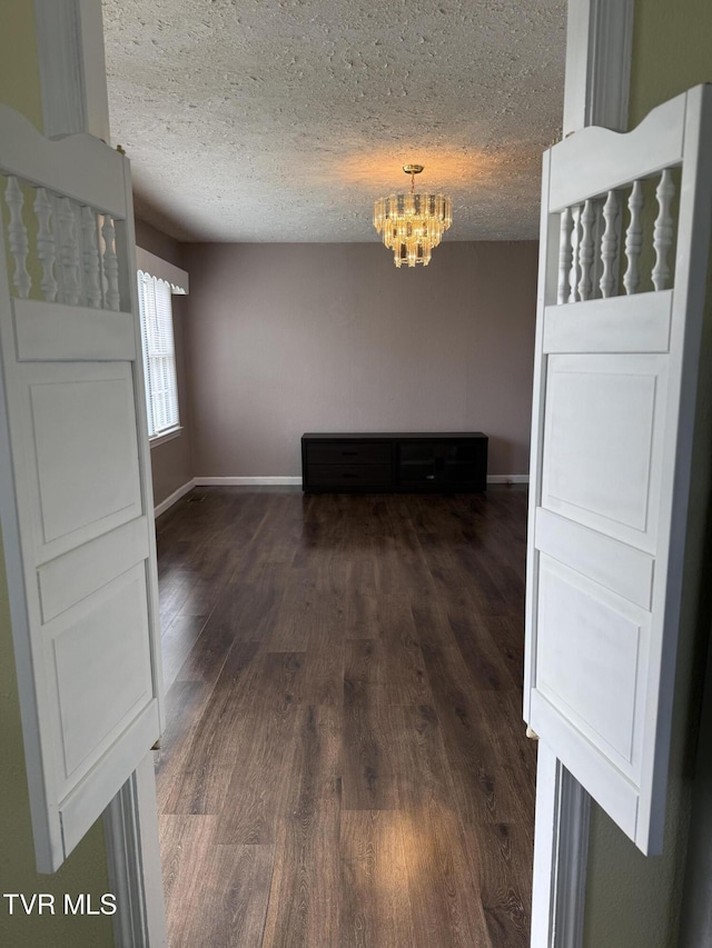 379 SW Oakland St, Abingdon, VA 24210 - empty room featuring a chandelier, dark wood-type flooring, a textured ceiling, and baseboards