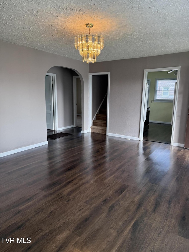 379 SW Oakland St, Abingdon, VA 24210 - unfurnished dining area with arched walkways, a chandelier, a textured ceiling, baseboards, and dark wood-style floors