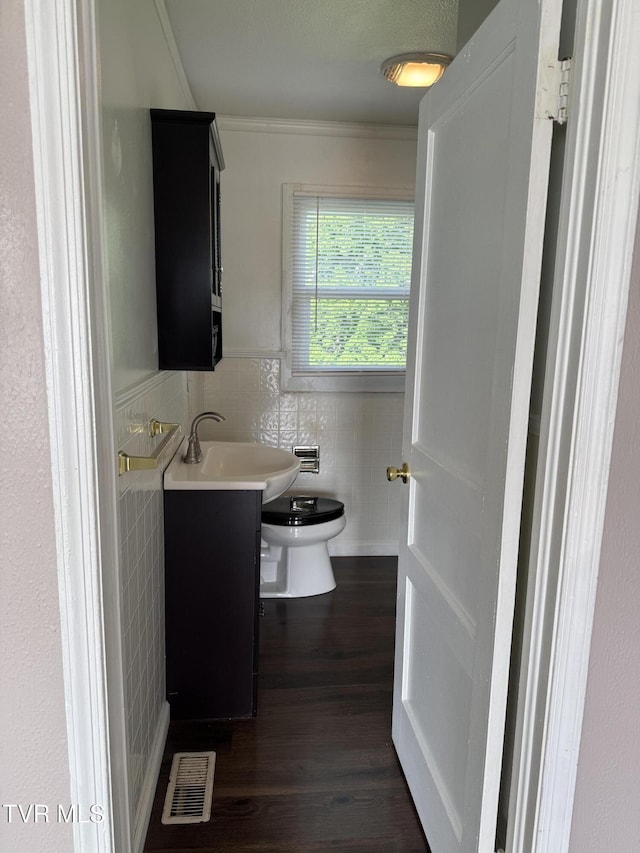 379 SW Oakland St, Abingdon, VA 24210 - half bath featuring tile walls, wood finished floors, ornamental molding, vanity, and wainscoting