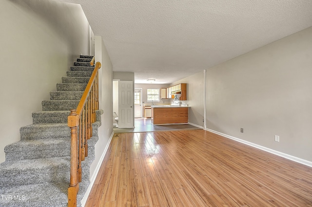 stairway with wood-type flooring, baseboards, and a textured ceiling