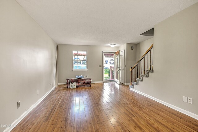 living room with hardwood / wood-style floors, baseboards, stairs, and a textured ceiling