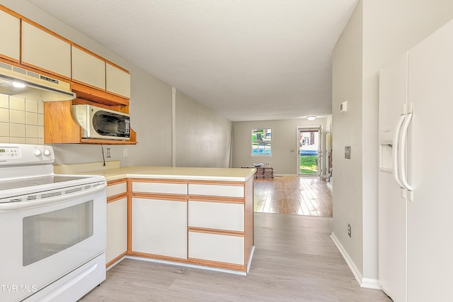 kitchen with white appliances, a peninsula, light wood-type flooring, under cabinet range hood, and tasteful backsplash