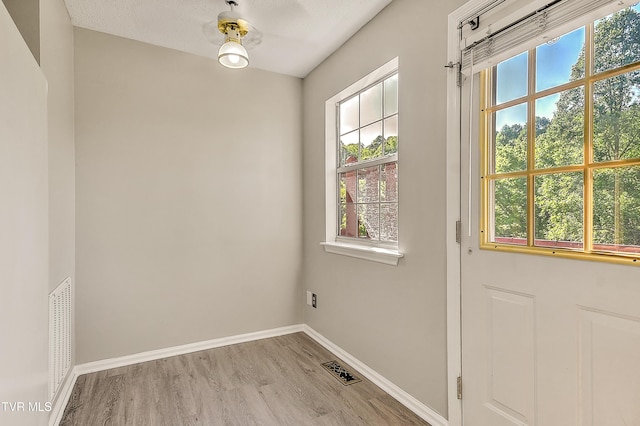 doorway to outside featuring wood finished floors, plenty of natural light, and baseboards