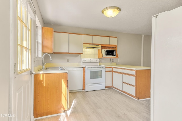 kitchen with white appliances, a sink, extractor fan, and light countertops