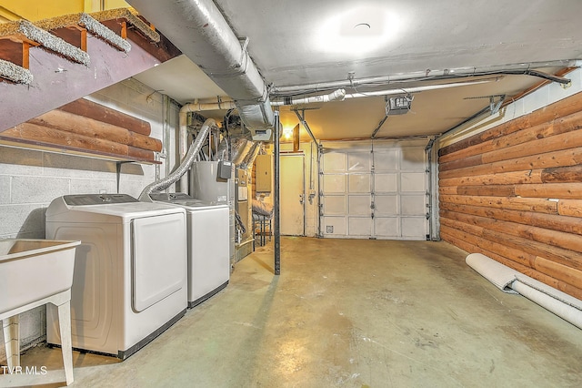 garage featuring washing machine and clothes dryer, electric panel, and a sink