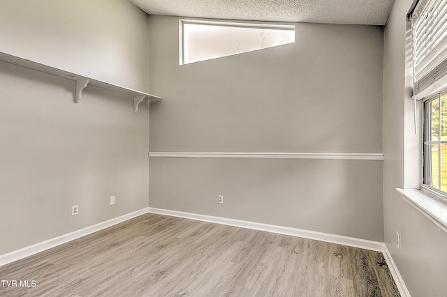 spare room with wood finished floors, baseboards, and a textured ceiling