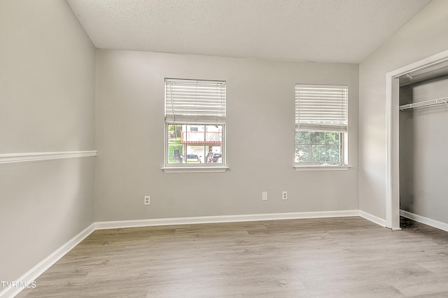 unfurnished bedroom featuring wood finished floors, a closet, baseboards, and a textured ceiling