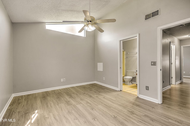 unfurnished bedroom with a textured ceiling, wood finished floors, ensuite bathroom, baseboards, and a ceiling fan