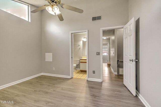unfurnished bedroom with wood finished floors, ensuite bathroom, baseboards, and ceiling fan