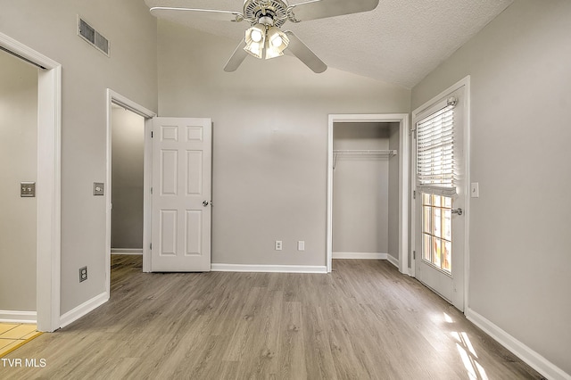 unfurnished bedroom featuring lofted ceiling, light wood finished floors, a closet, baseboards, and ceiling fan