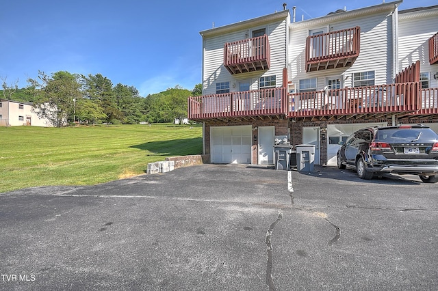 rear view of house with asphalt driveway, a lawn, and a garage
