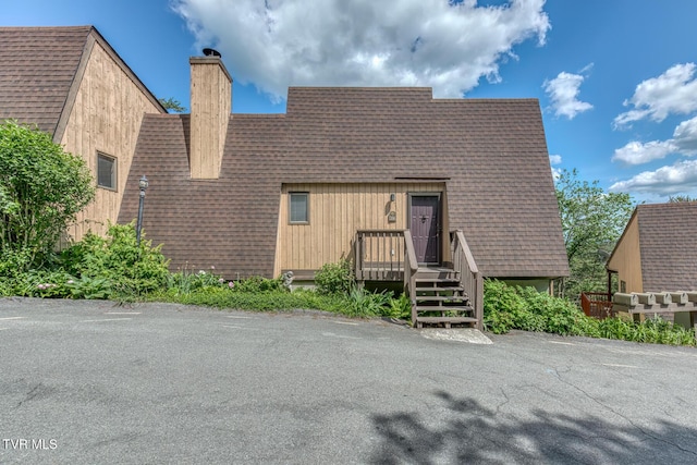 a-frame home with a chimney and a shingled roof