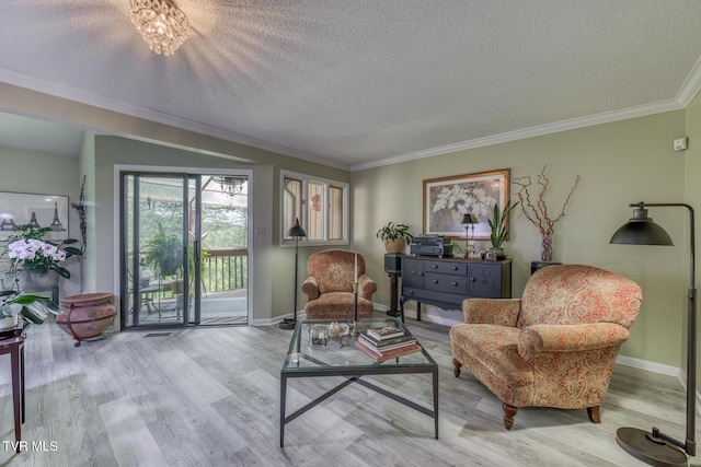 sitting room with wood finished floors, crown molding, a textured ceiling, and baseboards