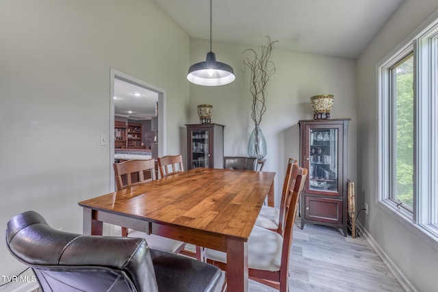 dining room with plenty of natural light, baseboards, and light wood-type flooring