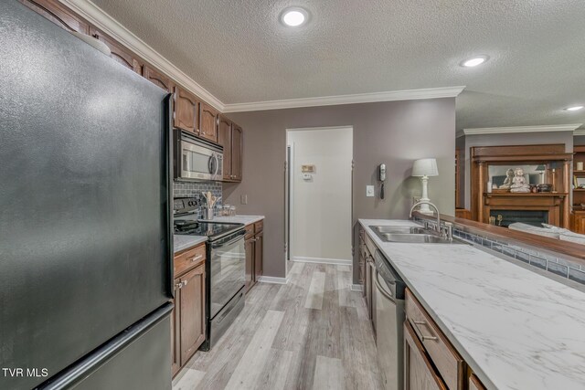 kitchen featuring black appliances, a sink, crown molding, light wood-style flooring, and a textured ceiling