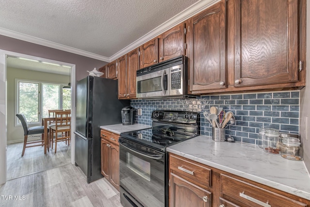 kitchen featuring black appliances, crown molding, light wood finished floors, a textured ceiling, and tasteful backsplash