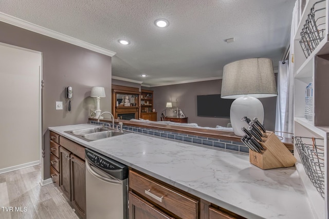 kitchen with stainless steel dishwasher, a textured ceiling, a sink, crown molding, and light wood-style flooring
