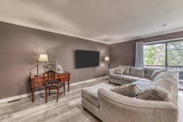 living room featuring a textured ceiling, ornamental molding, light wood-style flooring, and baseboards