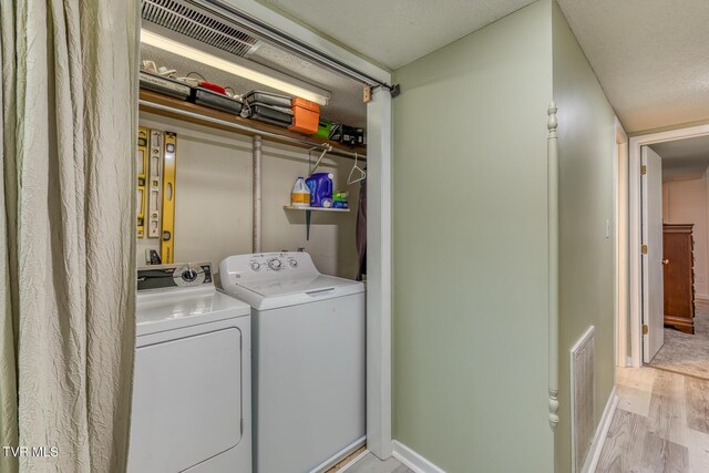 clothes washing area featuring separate washer and dryer, light wood-style floors, and baseboards