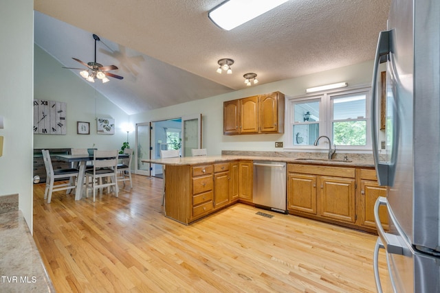 212 Old Castle Rd, Kingsport, TN 37660 - kitchen featuring appliances with stainless steel finishes, a peninsula, a sink, light wood finished floors, and brown cabinetry
