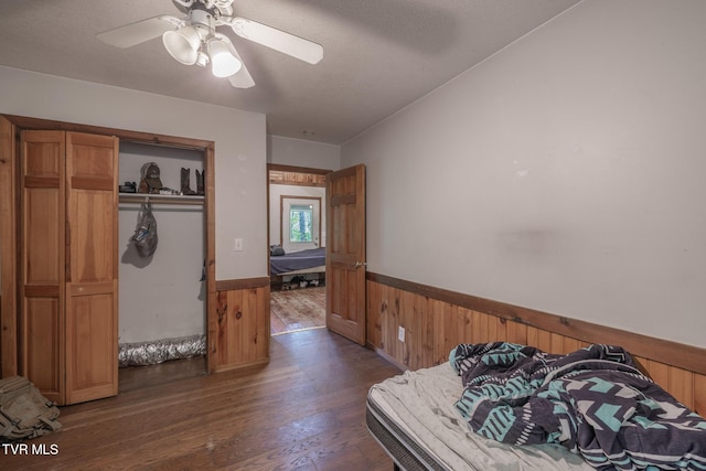 240 Old Railroad Grade Rd, Roan Mountain, TN 37687 - bedroom featuring a wainscoted wall, wood walls, wood finished floors, a closet, and a ceiling fan
