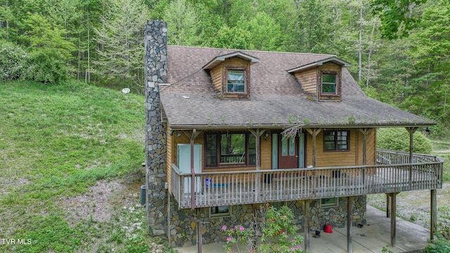 240 Old Railroad Grade Rd, Roan Mountain, TN 37687 - view of front of house with a chimney, a view of trees, roof with shingles, stone siding, and a deck