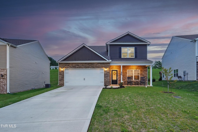 craftsman house featuring concrete driveway, covered porch, a yard, a garage, and stone siding
