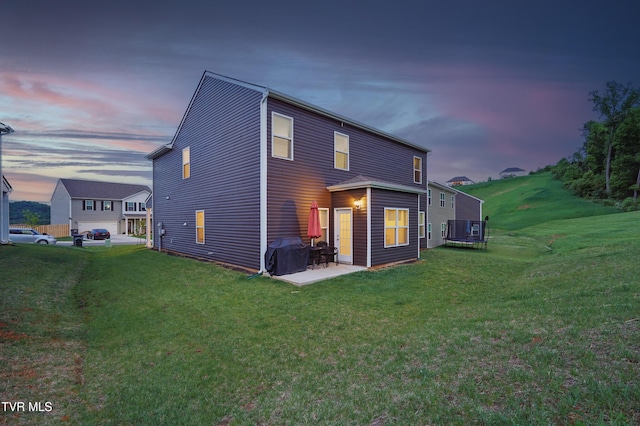 back of house at dusk with central AC unit, a lawn, and a patio area
