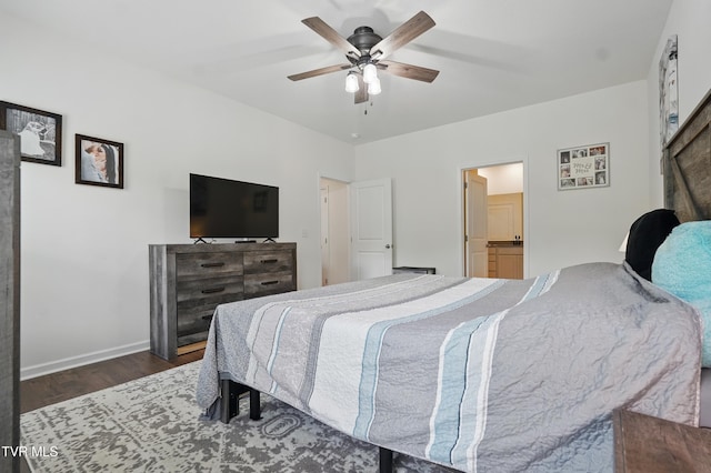 bedroom featuring wood finished floors, baseboards, ceiling fan, and ensuite bathroom