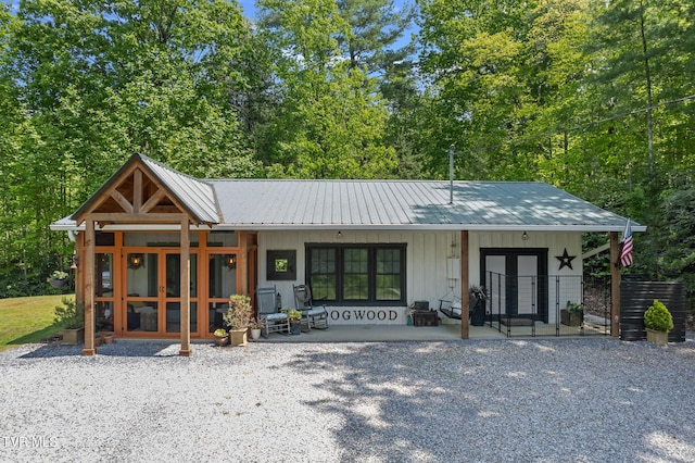 view of front facade featuring board and batten siding, french doors, a porch, and metal roof