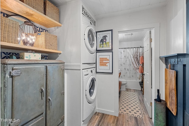 laundry room featuring wood finished floors, estacked washer and dryer, attic access, and ornamental molding